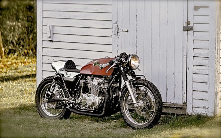 a motorcycle parked in front of a white building with a red seat on it's side