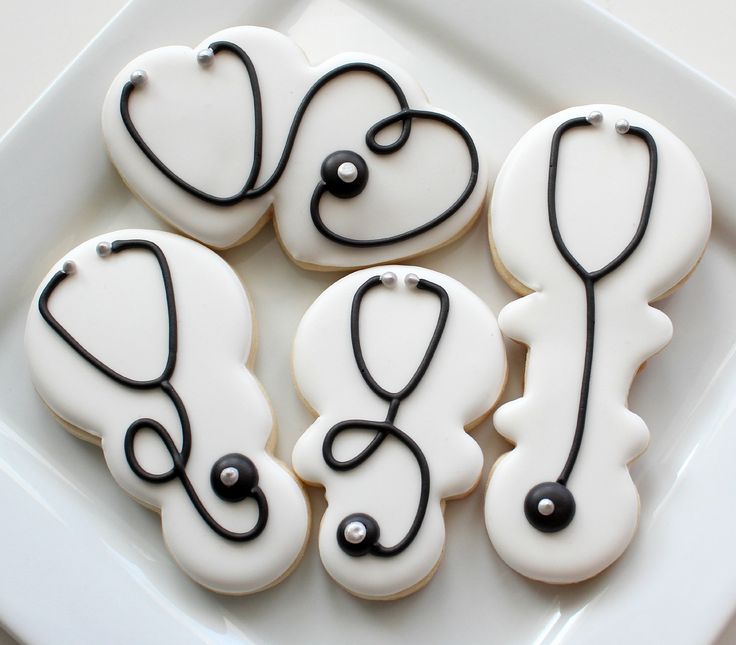 decorated cookies in the shape of medical symbols on a white plate with black trimmings