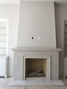 an empty living room with a fireplace and bookshelf in the corner, painted white