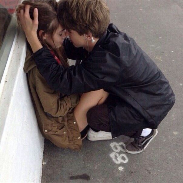 two people sitting on the ground with their arms around each other and one person touching his face