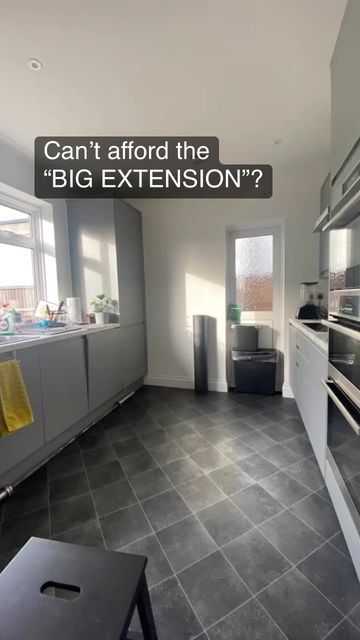 an empty kitchen with black tile flooring and white cabinets, has the words can't afford the big extension?