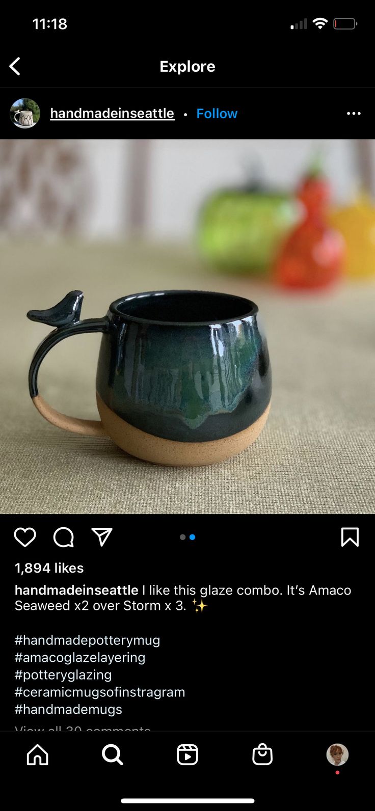 a black ceramic cup with a bird on it's handle is sitting on a table