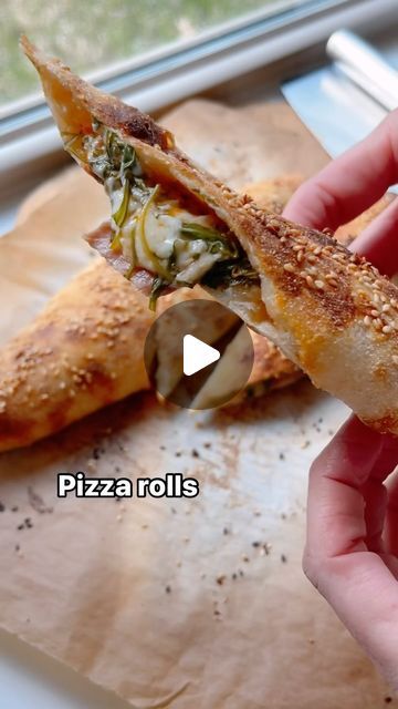 a person holding a piece of pizza in their hand with the words pizza rolls on it