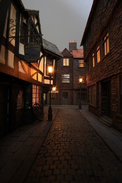 an alley way with brick buildings and street lamps on either side in the dark night