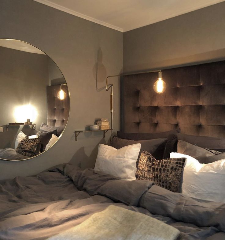 a bedroom with a large bed, mirror and lights on the headboard in front of it