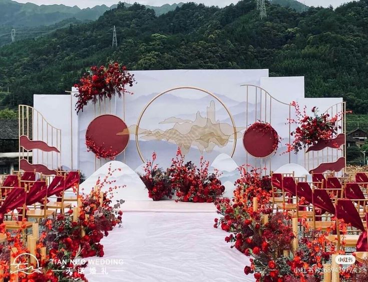 an outdoor ceremony set up with red flowers and gold chairs