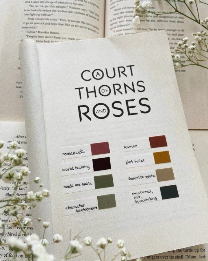 an open book with the title court thorns and roses on it next to flowers