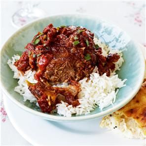 a bowl filled with rice and meat on top of a white plate next to a slice of bread