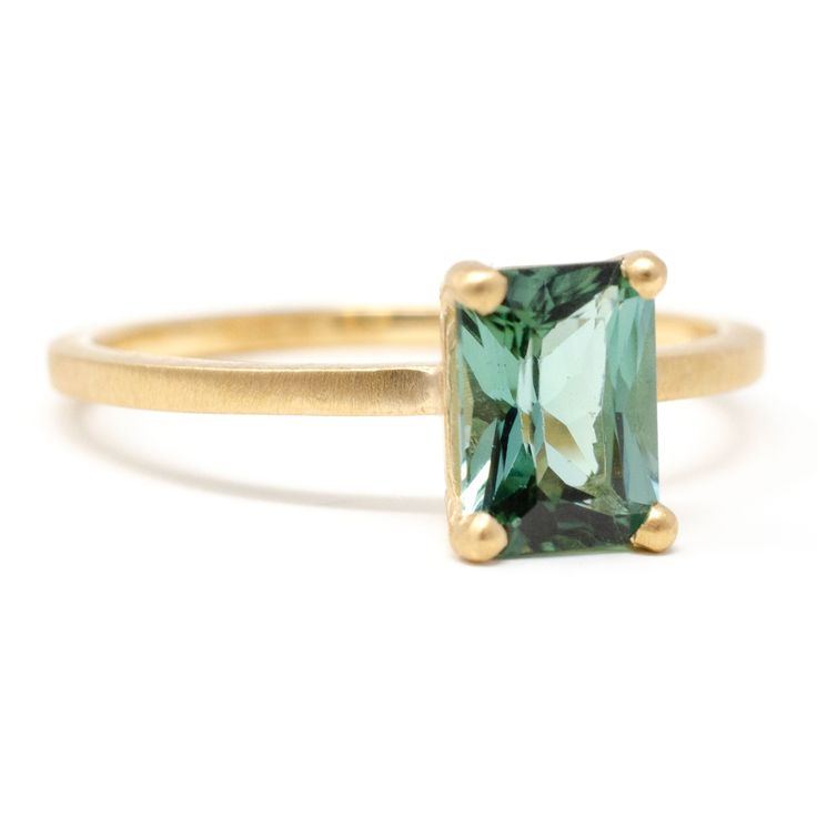 a gold ring with an emerald colored stone