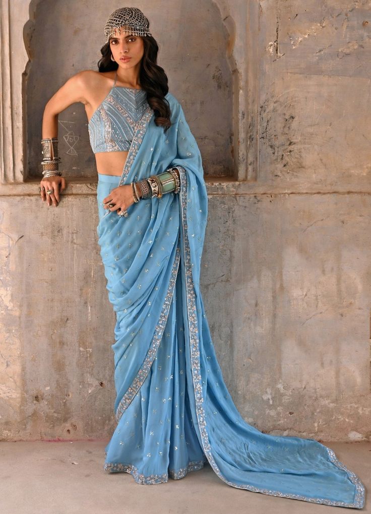 Features a hazel blue georgette embellished saree teamed with a halter neck blouse embellished with zardosi and glass beads detail. Includes a matching underskirt. Composition : Saree- Georgette, Blouse-Raw Silk, Underskirt- Satin Lycra Care: Dry Clean Only and Vacuum Storage This product can be customised for sleeves, length of blouse and neckline Delivery : 4-6 weeks as the product is hand crafted. Check Size Guide or choose MySize for free customisation (All Sizes above XL can be made at 15% additional cost) For more information and sizes please contact fabiliciousfashion@gmail.com or visit our Copenhagen studio.About the Designer : Born and brought up in the bustling city of Mumbai, Chamee and Palak come from a family of successful entrepreneurs and a deep-rooted love for textiles. The Halter Neck Blouses, Blouse Yoke, Drape Saree, Sari Blouse, Georgette Saree, Georgette Sarees, Fashion Icon, Indian Design, Wedding Looks