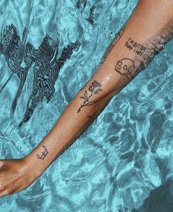 a person's arm in the water with tattoos on it