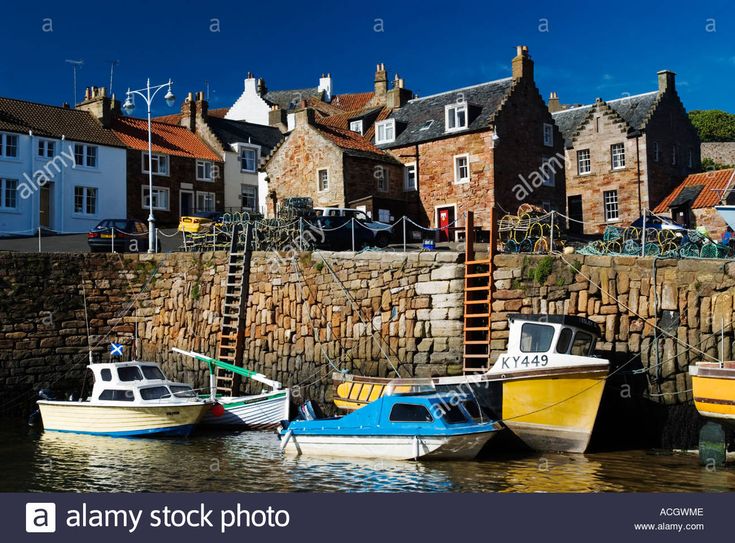 several small boats are docked in the water next to some buildings and a stone wall