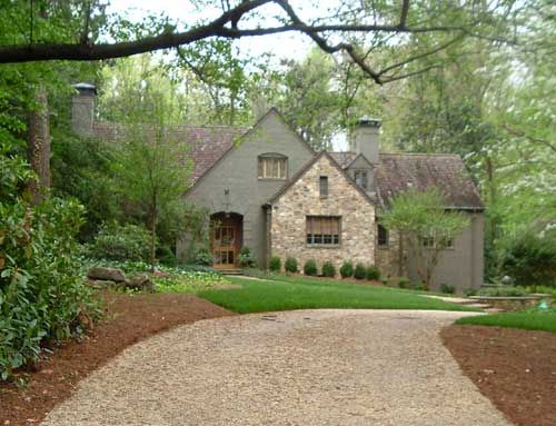 a driveway leading to a large house in the woods