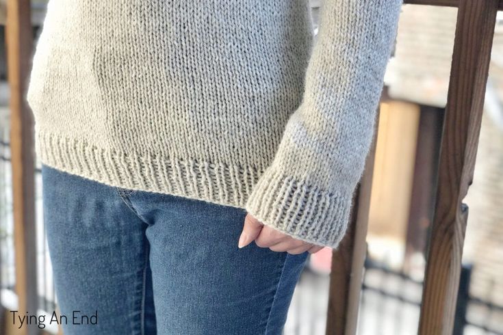 a woman standing on top of a wooden bench wearing a sweater and jeans with buttons