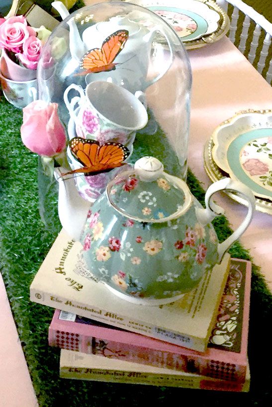 there is a tea pot with butterflies on it next to other plates and flowers in vases