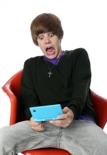 a young man sitting in a red chair holding a blue tablet with his mouth open