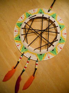 a paper plate with an arrow and some feathers on it, sitting on a table