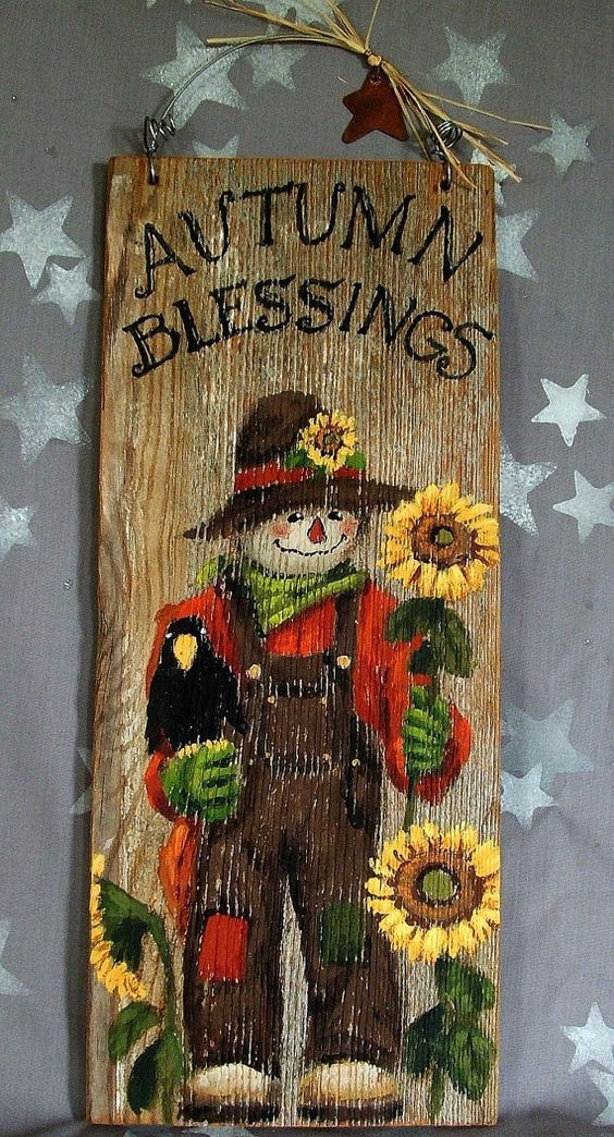 a wooden sign with an image of a scarecrow and sunflowers