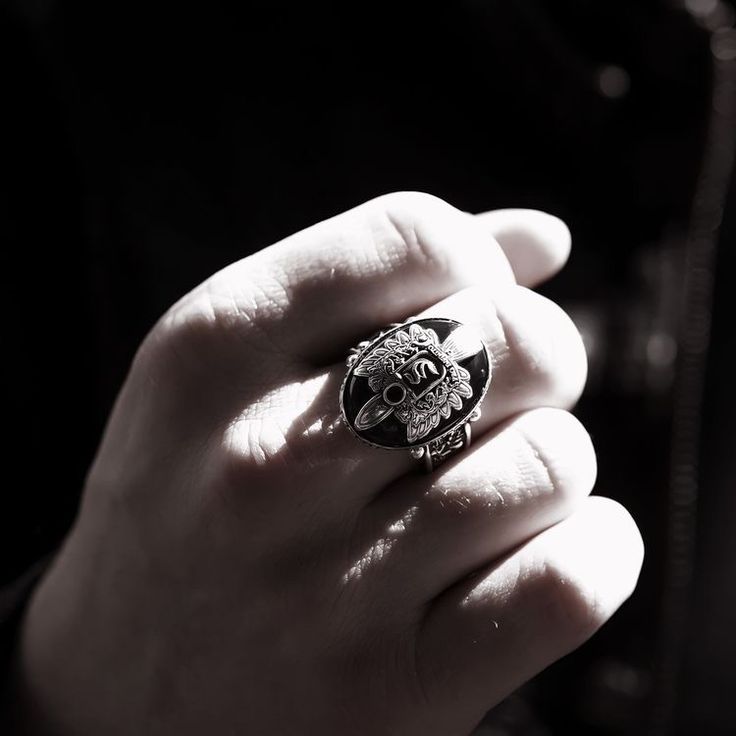 a person wearing a ring with a skull on it's middle finger, in black and white