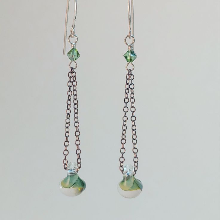 Glass green and clear button dangling from sterling silver chain, connected to a green swarovski crystal on a sterling wire twist, finished off with a sterling silver ear wire Wire Wrapping Diy, Asymmetrical Earrings, Wire Wrapped Earrings, Sterling Silver Chain, Ear Wire, Sterling Silver Chains, Diy Jewelry, Jewelry Earrings Dangle, Silver Chain