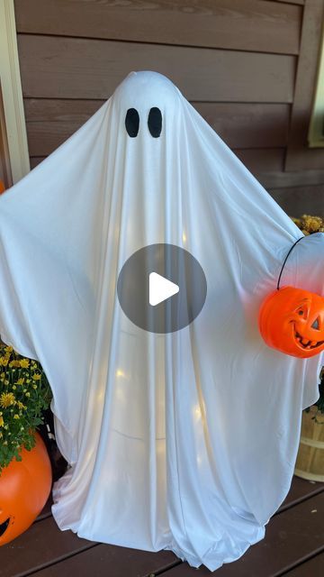 a white ghost with two pumpkins in front of it