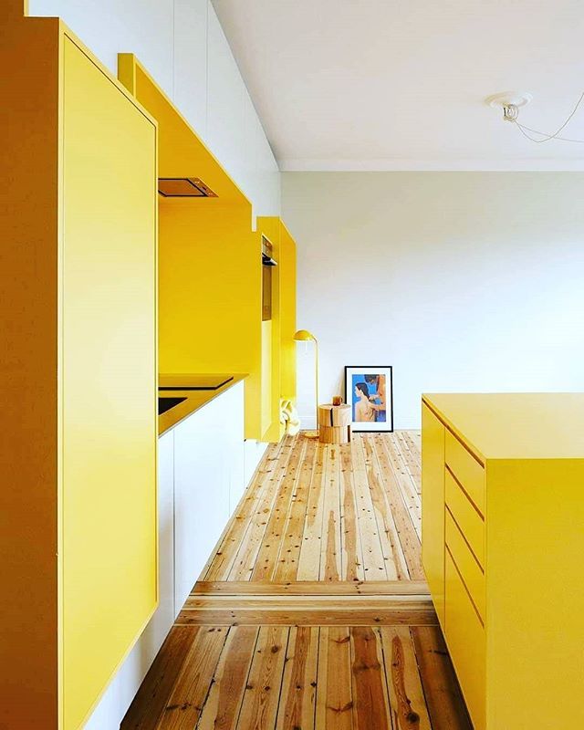 an empty room with wooden floors and yellow cabinets