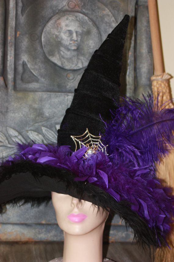 a black hat with purple feathers and a spider web on the top is sitting on a mannequin's head