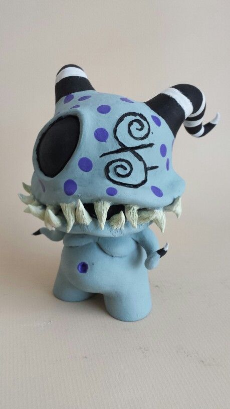 a blue and black monster figurine sitting on top of a white table next to a wall