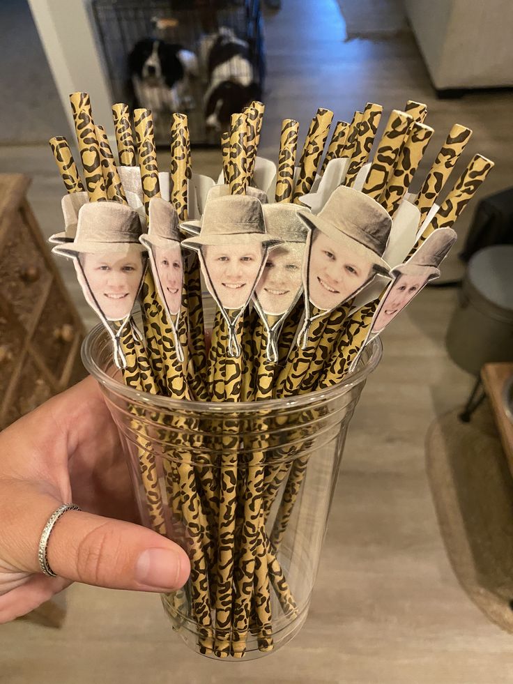 a person holding up a glass filled with stick pictures