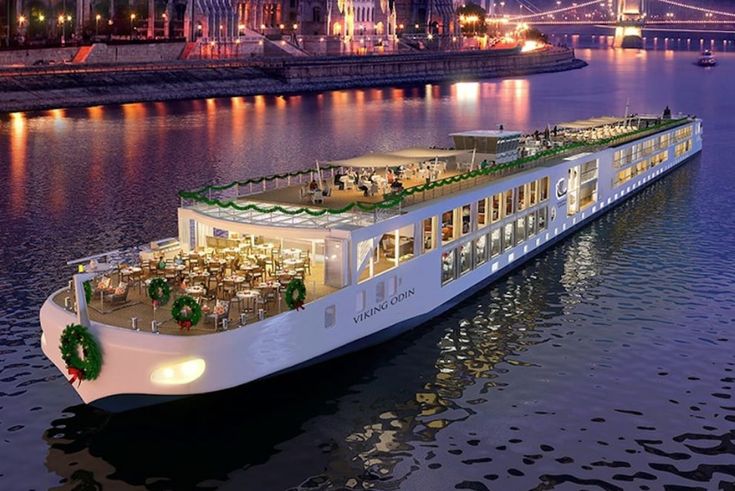 a large white boat floating on top of a river next to a bridge at night