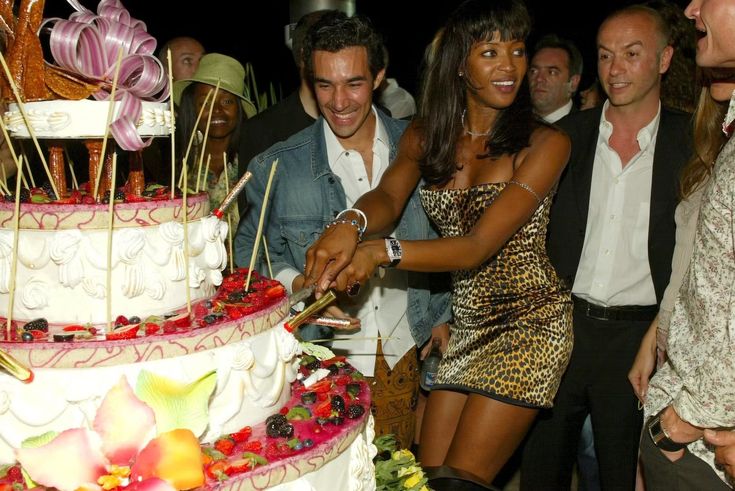 a group of people standing around a large cake