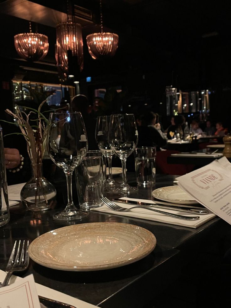 the table is set with wine glasses, silverware and menus in front of it