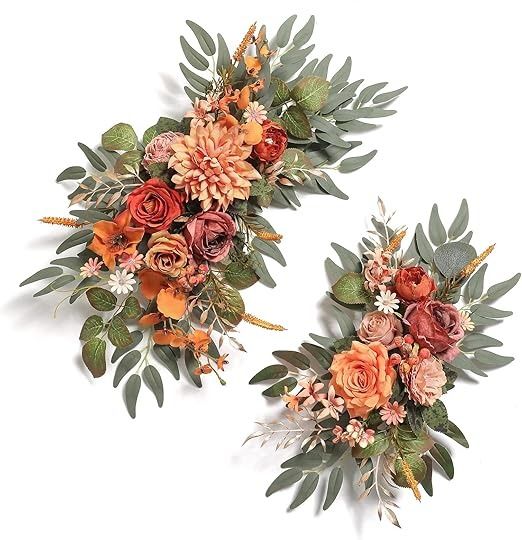 two orange and red flowers are arranged on the same piece of wall hangings with green leaves