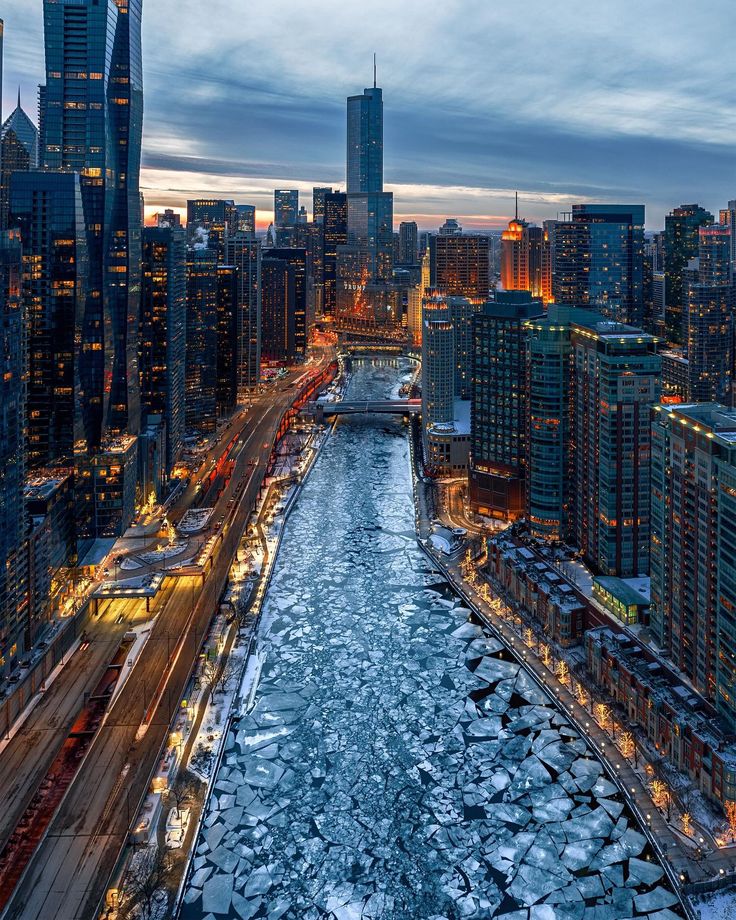 an aerial view of a river running through a large city at night with tall buildings in the background