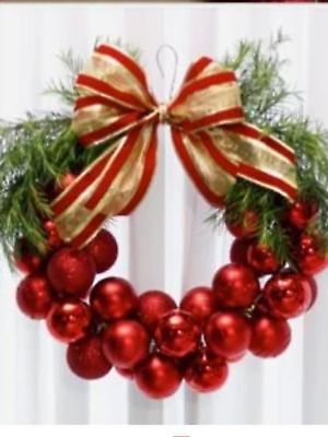 a christmas wreath with red ornaments and gold ribbon