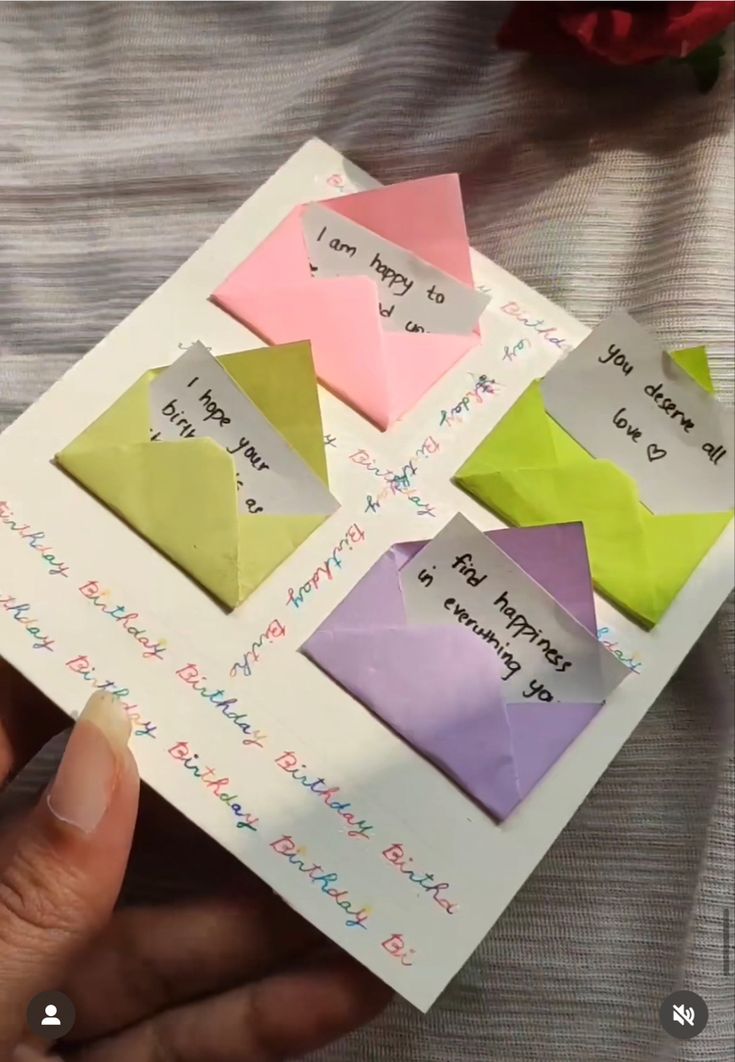 someone is holding up some origami pieces with words written on them in different colors