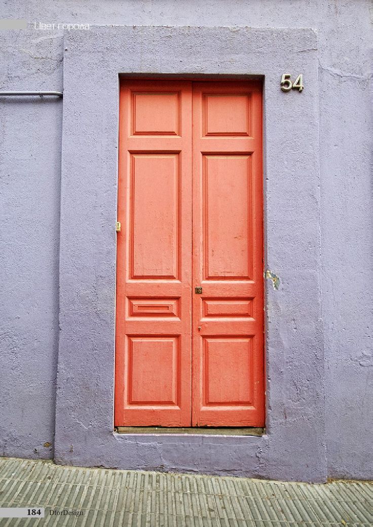 an orange door on the side of a gray building