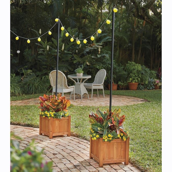 two wooden planters filled with flowers sitting on top of a brick patio next to a table