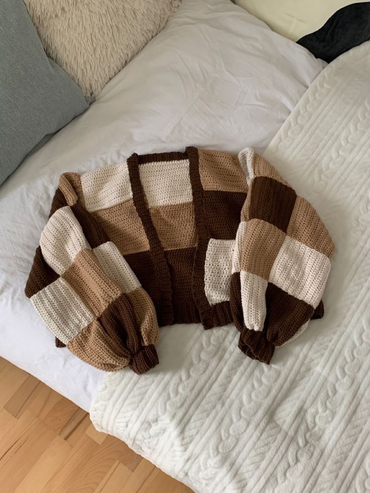 a brown and white sweater laying on top of a bed