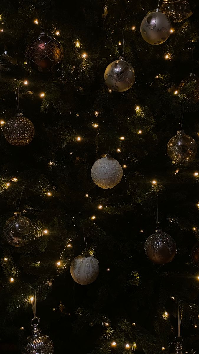 a christmas tree with ornaments hanging from it's branches and lights on the top