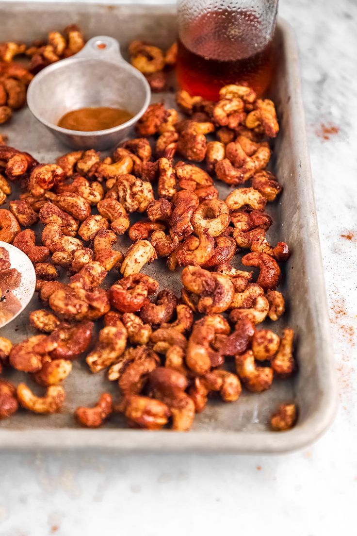 a tray filled with nuts next to a bottle of syrup