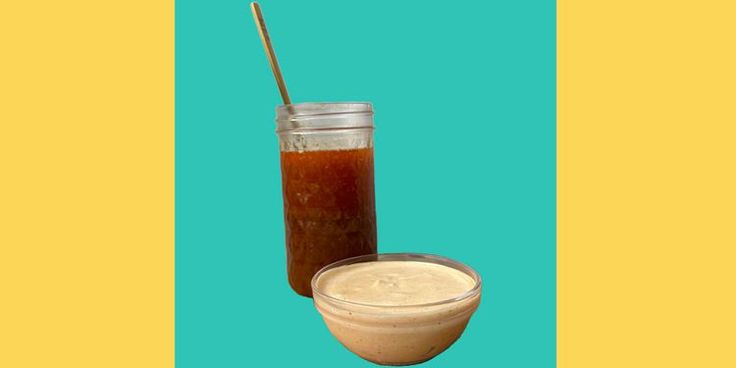 a glass jar filled with liquid next to a bowl full of sauce on a blue and yellow background