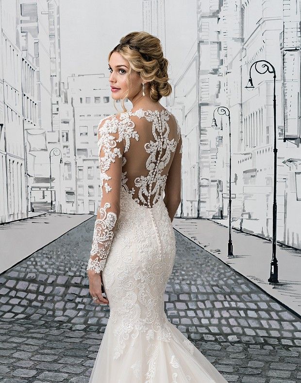 a woman in a white wedding dress standing on a brick road with her back to the camera