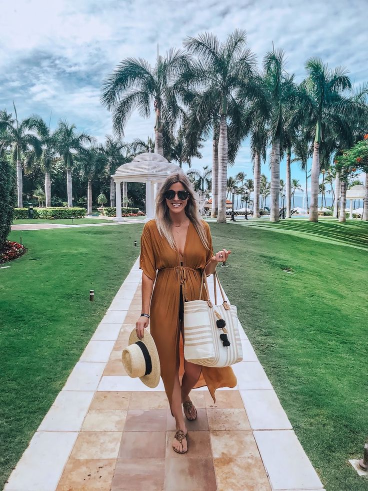 a woman walking down a path carrying a white purse