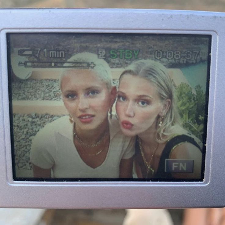 two young women are taking a selfie on a cell phone screen in front of the camera