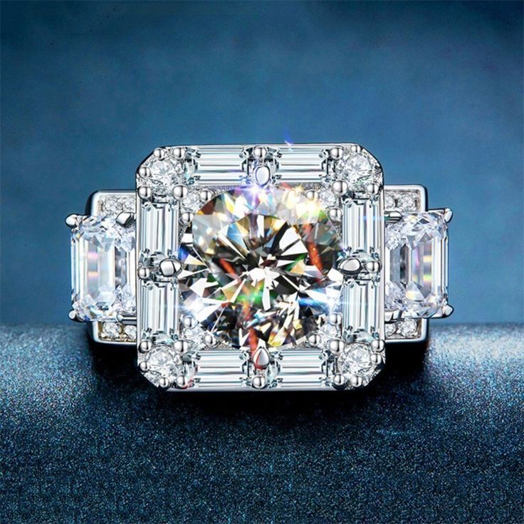 an engagement ring with assorted stones and diamonds on the side, in front of a blue background