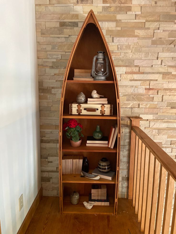 a wooden shelf with books and vases on top of it next to a brick wall