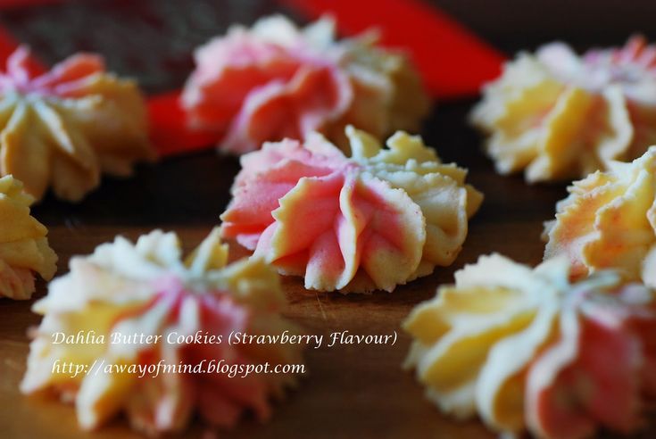 some colorful cookies are sitting on a wooden table with red and yellow frosting around them