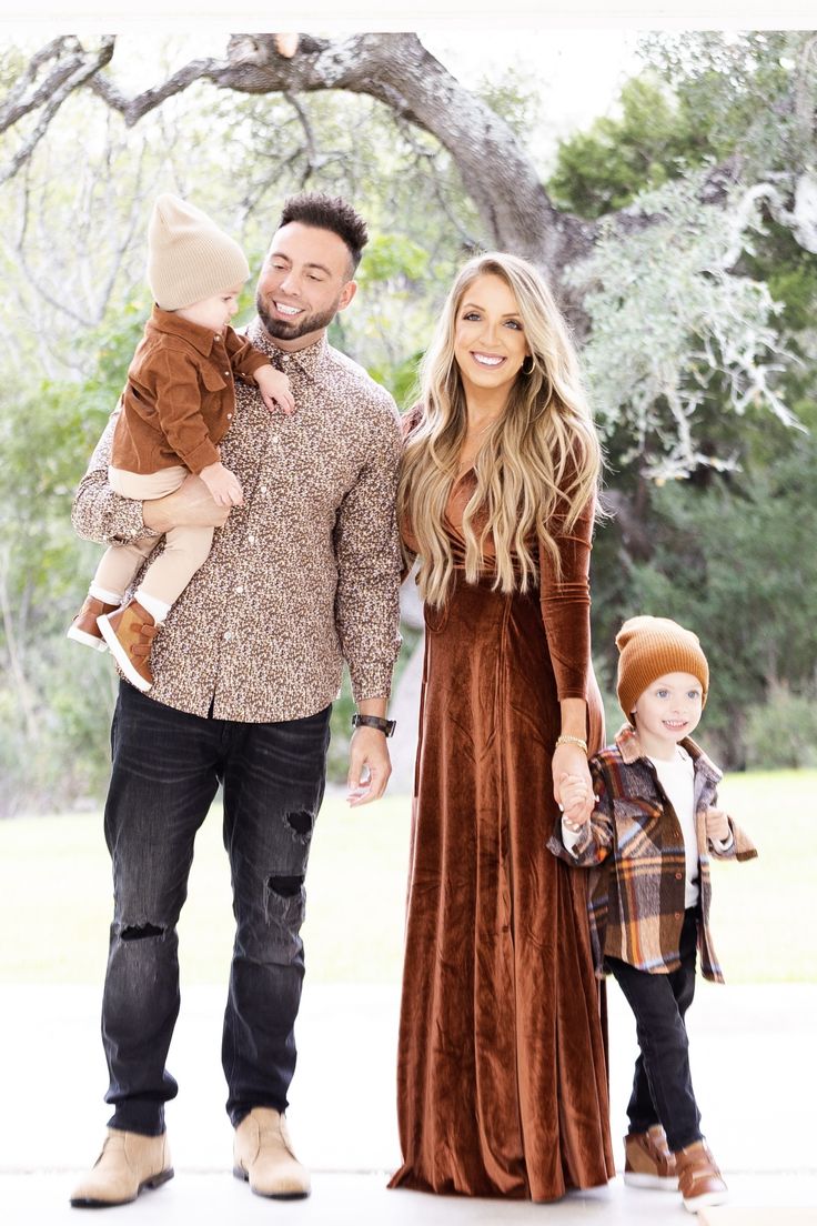 a man, woman and child are standing in front of a tree