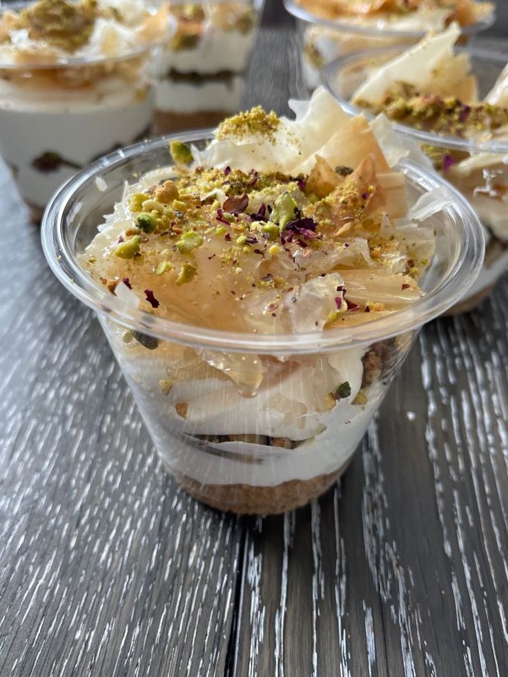 several desserts in plastic cups sitting on a wooden table